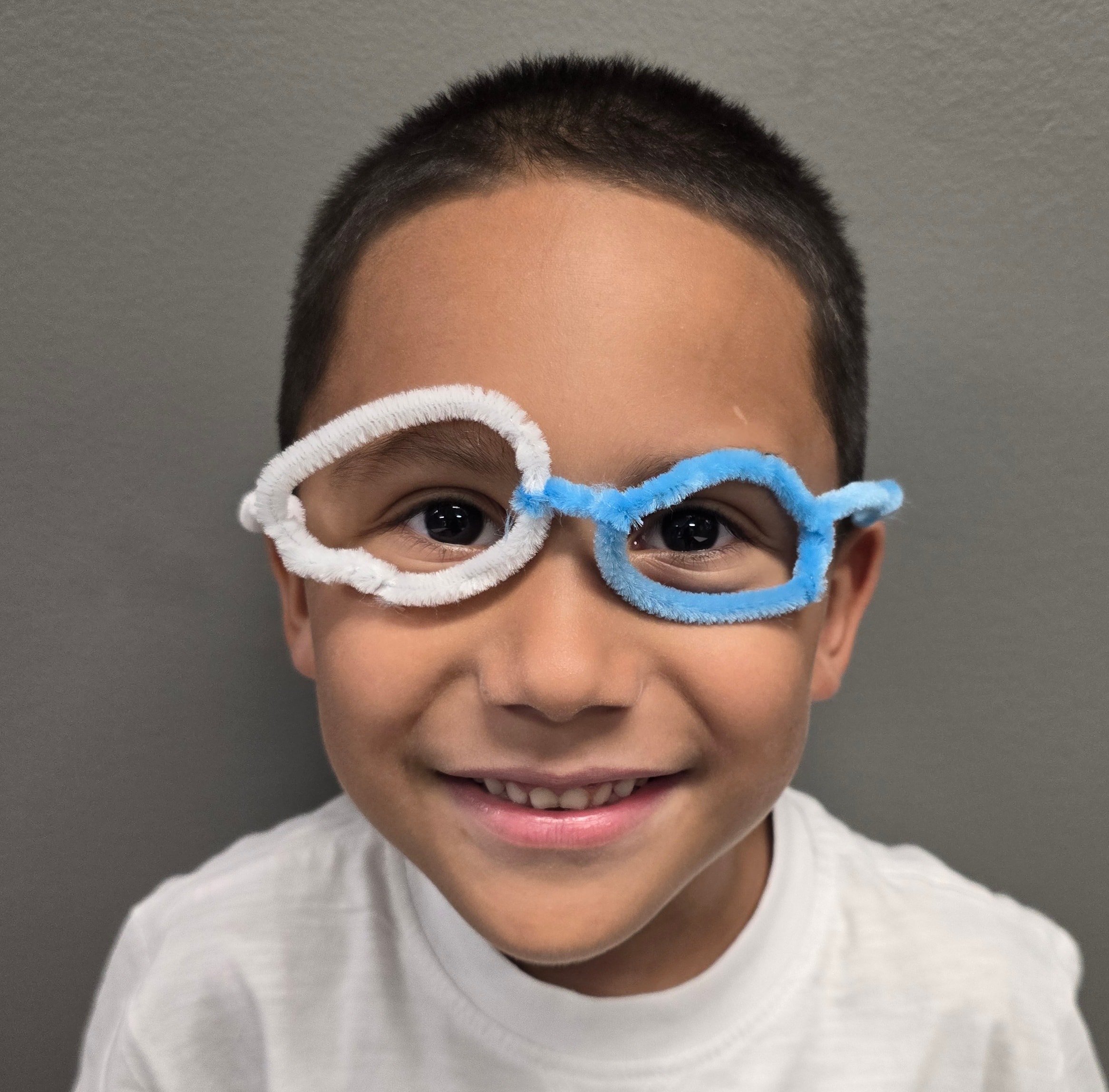 Camper wearing pipe-cleaner glasses made at camp