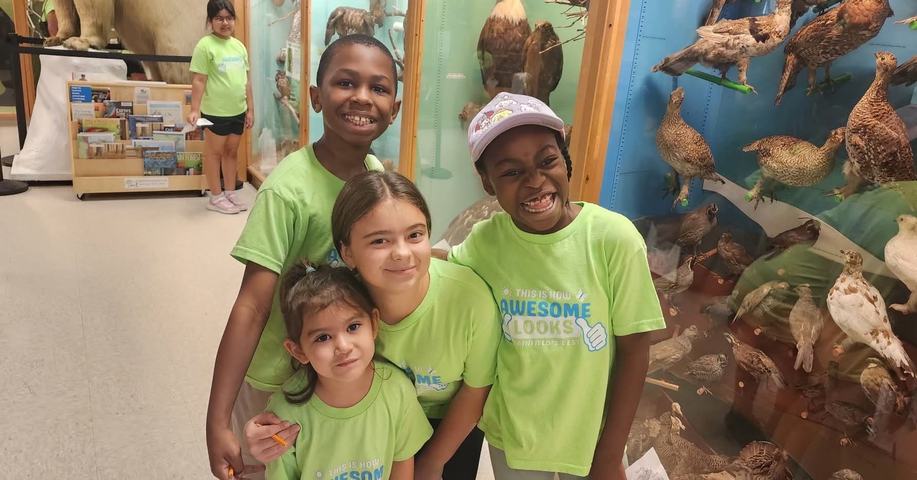 Campers in green camp shirts smiling at a museum exhibit